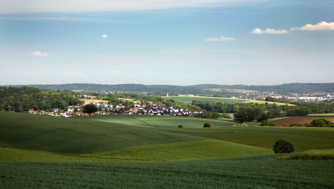 Panoramaansicht eines Dorfes zwischen grünen Hügeln